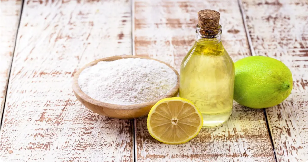 Vinagre branco, bicarbonato de sódio e limões em uma bancada, representando ingredientes naturais para limpeza